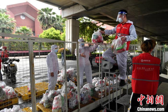 图为：永辉超市工作人员将商品递给管控区内的工作人员。　吕明 摄