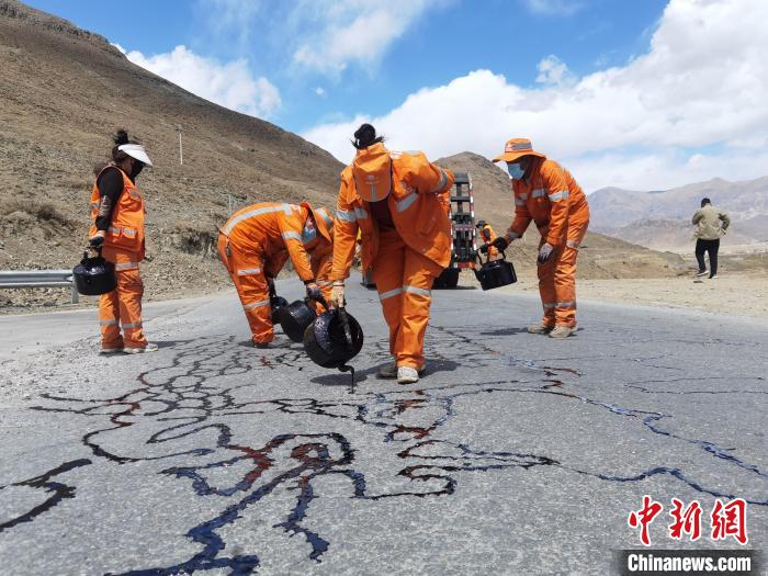 图为在基层农村公路，女护路员正熟练地开展沥青灌缝作业。　西藏自治区交通运输厅供图