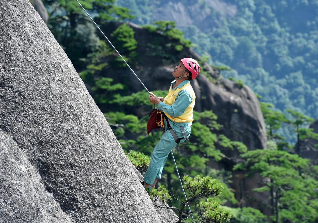 8月15日，李培生在黄山风景区的悬崖峭壁间清捡垃圾。新华社记者 周牧 摄