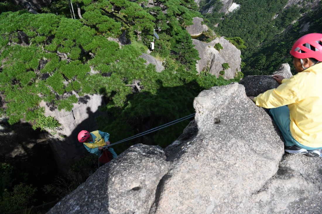 8月15日，李培生（左）在黄山风景区的悬崖峭壁间清捡垃圾。新华社记者 周牧 摄