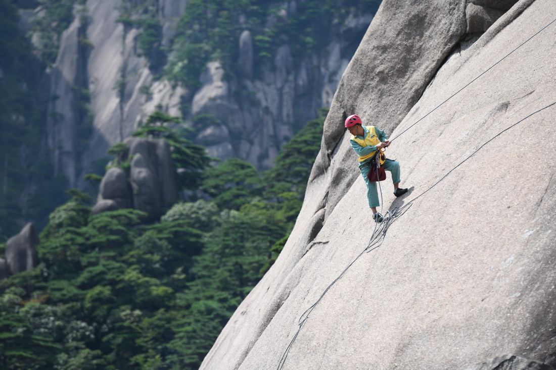 8月14日，李培生在黄山风景区的悬崖峭壁间清捡垃圾。新华社记者 张端 摄