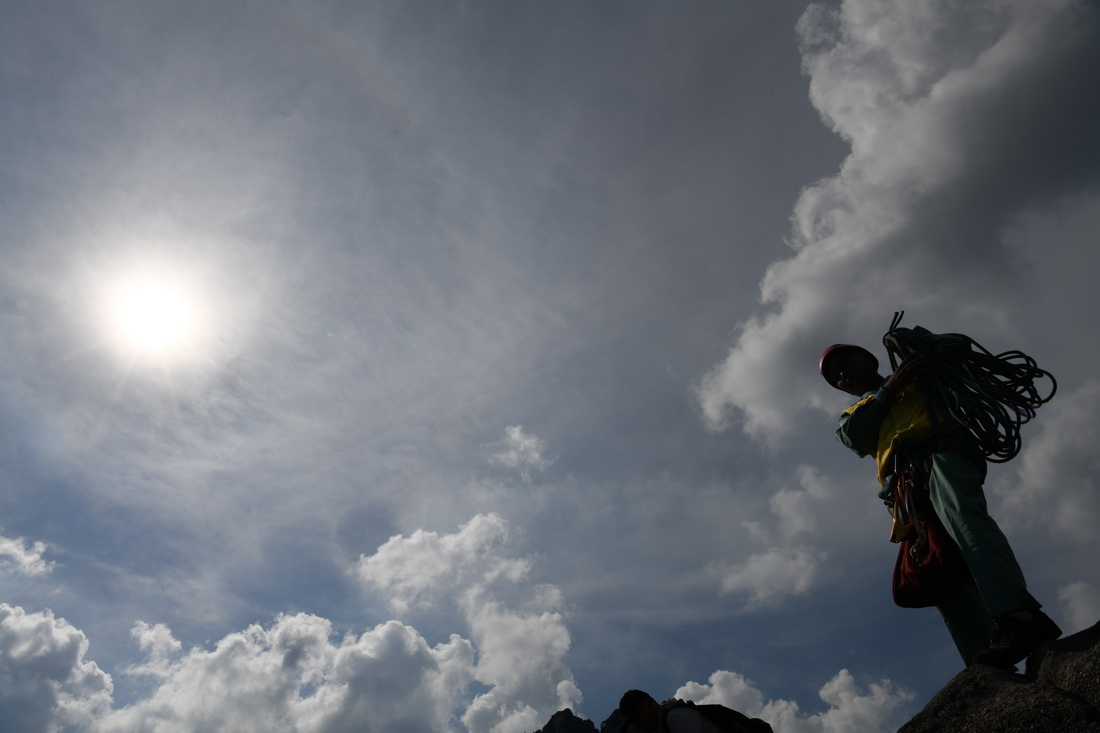 8月14日，李培生在黄山风景区的悬崖峭壁间清捡完垃圾准备离开。新华社记者 张端 摄